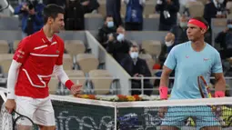 Petenis Novak Djokovic (kiri) dan Rafael Nadal saling memandang sebelum pertandingan final Prancis Terbuka 2020 di Stadion Roland Garros, Paris, Prancis, Minggu (11/10/2020). Dengan kemenangan ini, Nadal menyamai rekor Roger Federer dengan meraih 20 gelar Grand Slam. (AP Photo/Michel Euler)