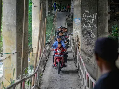 Pengendara sepeda motor melintas  jalur alternatif khusus motor pada jembatan yang melintasi Sungai Ciliwung menuju arah Puncak di kawasan Katulampa, Kabupaten Bogor, Jawa Barat, Kamis (11/04/2024). (merdeka.com/Arie Basuki)