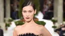 <p>Model Bella Hadid berpose mengenakan gaun hitam koleksi terbaru dari Oscar de la Renta berjalan di atas catwalk selama New York Fashion Week, AS (12/2). Gaun yang dikenakan Bella Hadid dihiasi motif simetris. (AFP Photo/Slaven Vlasic)</p>