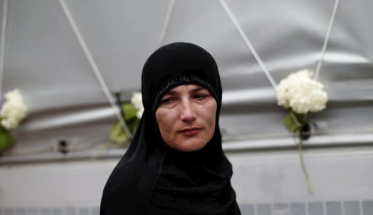 Seorang wanita tampak lesu saat berdiri di depan truk yang membawa 136 peti mati korban pembantaian Srebrenica, di desa Visoko, Bosnia-Herzegovina, Kamis, (9/7/2015). Rencananya, jenazah akan dimakamkan pada 11 Juli mendatang. (REUTERS / Stoyan Nenov)