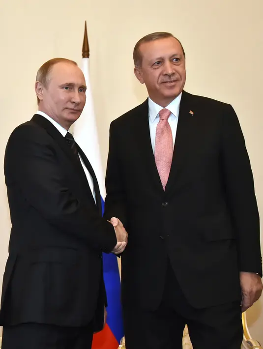 Presiden Rusia, Vladimir Putin dan Presiden Turki Tayyip Erdogan bersalaman saat menggelar pertemuan di St. Petersburg, Rusia, (9/8). Hubungan kedua negara sempat tegang akibat penembakan jet tempur Rusia oleh militer Turki. (AFP PHOTO/ALEXANDER NEMENOV)