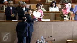 Menteri Susi Pudjiastuti (tengah) berjabat tangan dengan ketua Komisi IV Edie Prabowo usai menyerahkan pandangan pemerintah dalam Sidang Paripurna DPR di Gedung DPR, Jakarta, Selasa (15/3/2016). (Liputan6.com/Johan Tallo)