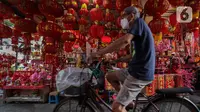 Pesepeda melintas di depan penjual pernak-pernik Imlek di Kawasan Petak Sembilan, Glodok, Jakarta, Minggu (7/2/2021). Tahun ini perayaan Hari Raya Imlek jatuh pada tanggal 12 Februari 2021 mendatang. (Liputan6.com/Johan Tallo)