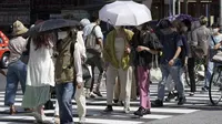 Orang-orang berjalan di atas penyeberangan pejalan kaki di bawah terik matahari di Tokyo, Senin (30/5/2022). Cuaca panas pada hari Senin telah ditetapkan dengan suhu naik lebih dari 27 derajat Celcius (80,6 derajat Fahrenheit) di Tokyo, menurut Badan Meteorologi Jepang. (AP Photo/Eugene Hoshiko)