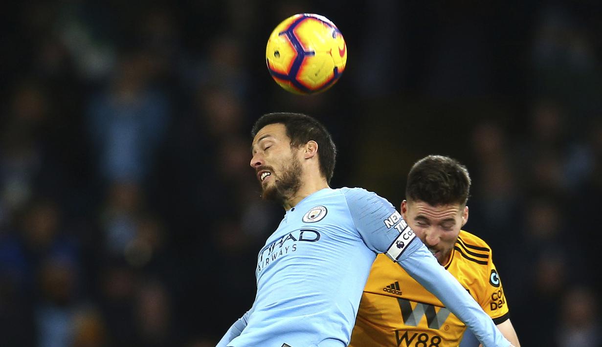 Gelandang Manchester City, David Silva, duel udara dengan pemain Wolverhampton Wanderers, Matt Doherty, pada laga Premier League di Stadion Etihad, Manchester, Senin (14/1). Manchester City menang 3-0 atas Wolverhampton Wanderers. (AP/Dave Thompson)