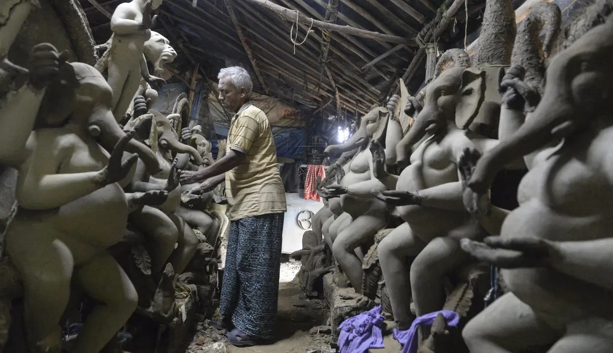 Perajin membuat patung Dewa Ganesha di sebuah bengkel di pinggiran Hyderabad, India, Rabu (18/8/2021). ​Patung ramah lingkungan yang dibuat jelang perayaan Ganesh Chaturthi tersebut dibuat dari lumpur, serat rami, dan bambu untuk mengurangi polusi air. (NOAH SEELAM/AFP)