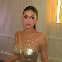 Bak golden barbie modern, Kylie Jenner tampil memukau dalam balutan gaun emas metalik rancangan Ashi Studio. [@makeupbyariel].