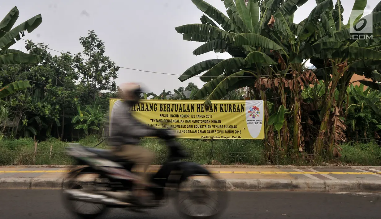 Motor melintas di dekat spanduk larangan di kawasan Pulomas, Jakarta, Rabu (4/7). Larangan berjualan hewan kurban radius 1 kilometer dari Equestrian Park bagian dari sterilisasi. (Merdeka.com/Iqbal S. Nugroho)
