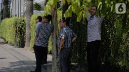 Sejumlah pria berdiri di bawah pohon selama gelombang panas di Jakarta, Selasa (22/10/2019).  BMKG memprediksi wilayah Indonesia akan mengalami panas selama kurang lebih satu minggu ini. Hal ini dikarenakan matahari yang berada dekat dengan jalur khatulistiwa. (Liputan6.com/Faizal Fanani)