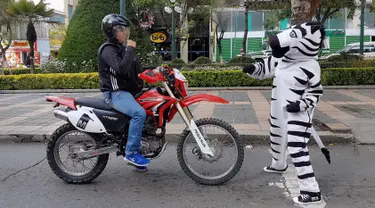 Seorang warga berpakaian seperti zebra berbincang dengan pengendara motor sebagai bagian dari program pendidikan di jalan di La Paz, Bolivia,(5/12). Kegiatan ini cukup menyita perhatian sejumlah pengendara. (REUTERS/David Mercado)