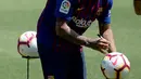 Pemain baru Barcelona, Arturo Vidal menandatangani bola selama presentasi dirinya di stadion Camp Nou, Spanyol, (6/8). Vidal resmi diboyong Barcelona dengan kontrak selama tiga tahun. (AFP Photo/Josep Lago)