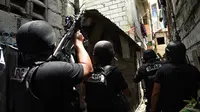 Dalam gambar yang diambil pada 5 September 2016, anggota tim SWAT Kepolisian Filipina mengambil posisi sambil membawa senjata mereka saat mengepung sebuah rumah dalam operasi anti-narkoba di kawasan pemukiman di pinggiran Kota Manila. (TED Aljibe/AFP)