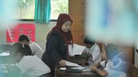 Seorang guru membagikan soal Ujian Nasional (UN) kepada para peserta di SDN 04 Jakarta, Senin (18/5/2015). Sebanyak 153.266 peserta didik SD/MI dan sederajat di Jakarta mengikuti UN yang digelar 18-20 Mei. (Liputan6.com/Herman Zakharia)