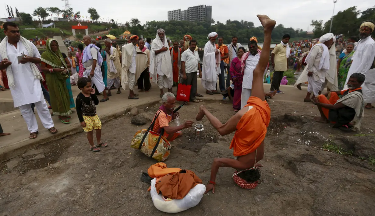 Sadhu, sebutan orang suci umat Hindu, berdiri terbalik dengan kepalanya saat menerima sedekah selama Festival Pitcher di Nashik, , India, (28/8/2015). (REUTERS/Danish Siddiqui)