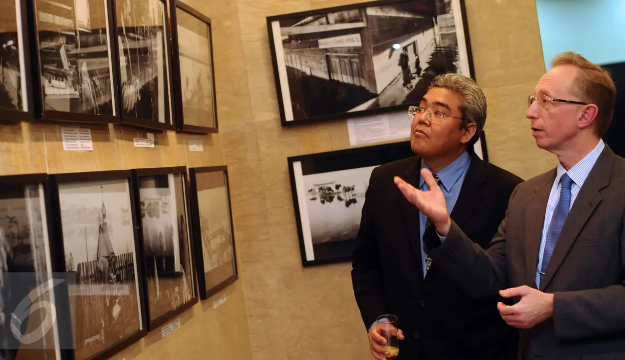 Duta Besar Rusia untuk Indonesia, Mikhail Galuzin (kanan) bersama salah satu pengunjung melihat hasil liputan pewarta foto Rusia, Andrey Stenin di Russian Center for Science and Culture, Jakarta, Selasa (22/12/2015). (Liputan6.com/Helmi Fithriansyah)