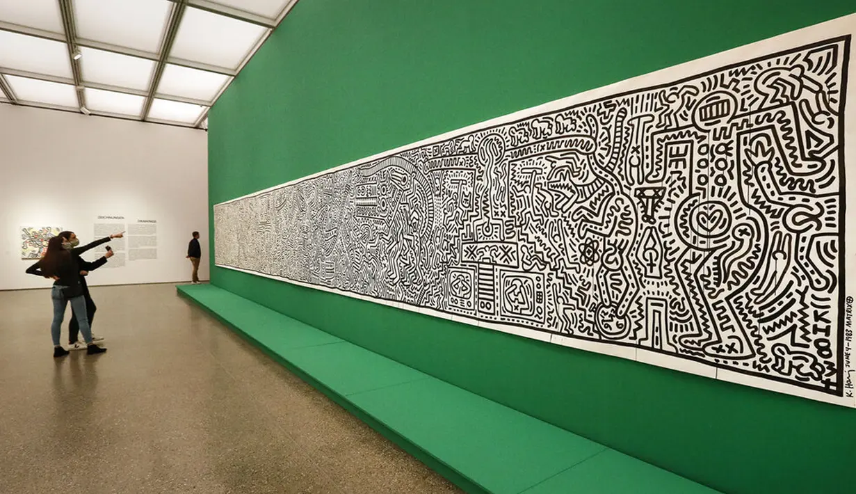 Pengunjung mengamati karya seni seniman Amerika Serikat Keith Haring saat pameran di Museum Folkwang, Essen, Jerman, Selasa(1/9/2020). Keith Haring merupakan seniman jalanan asal New York yang meninggal akibat komplikasi AIDS pada tahun 1990. (AP Photo/Martin Meissner)