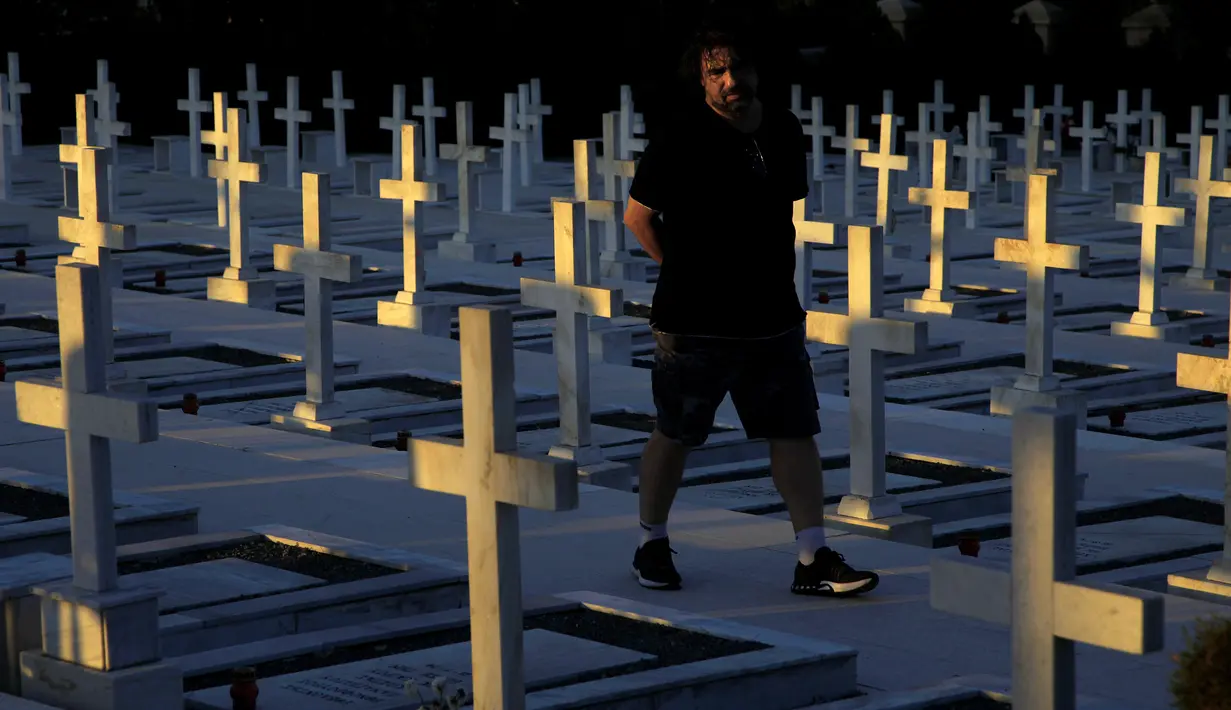 Seorang pria berjalan dekat kuburan tentara yang tewas dalam invasi Turki ke Siprus di pemakaman militer Tymvos Macedonitissas, Nicosia, Siprus, Senin (20/7/2020). Ribuan orang Yunani dan tentara Siprus tewas selama invasi Turki ke Pulau Siprus pada tahun 1974. (AP Photo/Petros Karadjias)