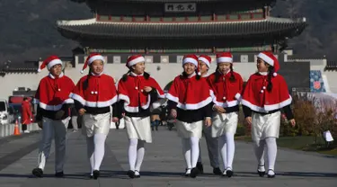 Anak-anak Korea Selatan mengenakan pakaian Santa Claus berjalan di depan Istana Gyeongbokgung, Seoul, Jumat (30/11). Anak-anak tersebut bersiap meluncurkan kampanye penggalangan dana akhir tahun dari The Salvation Army. (Jung Yeon-je/AFP)