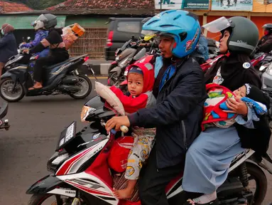 Pemudik sepeda motor saat berboncengan dengan anak-anak melintasi Simpang Jomin, Jawa Barat, Rabu (19/4/2023). (Liputan6.com/Angga Yuniar)