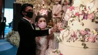 Pengantin memakai masker saat simulasi penerapan protokol kesehatan resepsi pernikahan di era new normal di Jakarta, Kamis (9/7/2020). Kegiatan ini bertujuan untuk mengedukasi masyarakat dalam acara pernikahan guna mencegah penyebaran COVID-19. (Liputan6.com/Faizal Fanani)