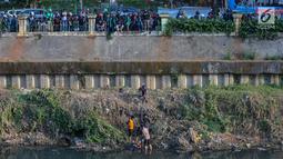 Polisi dan warga mengamankan terduga pelaku pelecehan seksual yang menceburkan diri di Kali Ciliwung, Manggarai, Jakarta, Minggu (7/6/2019). Pelaku menceburkan diri dan pura-pura pingsan saat dikejar massa dengan modus mencegat korban perempuan mendapat hadiah. (Liputan6.com/Fery Pradolo)