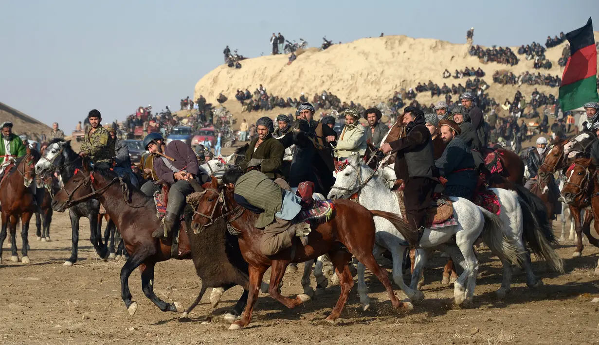 Penunggang kuda Afghanistan memperebutkan bangkai saat pertandingan olahraga tradisional Buzkashi di Mazar-i-Sharif, Afghanistan (20/12). Mereka merebutkan bangkai seekor binatang ternak yang dibawa di sekitar penanda atau bendera. (AFP/Farshad Usyan)