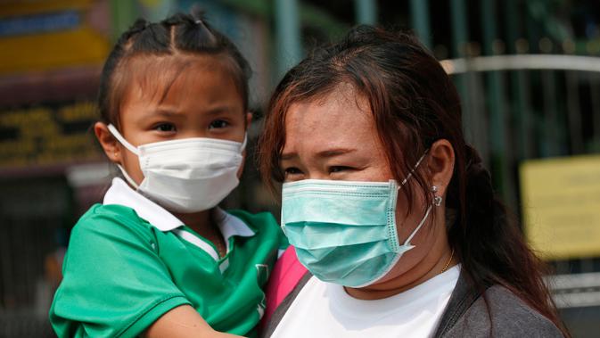 Seorang anak perempuan mengenakan masker saat dijemput orang tuanya di Bangkok, Thailand (30/1). Partikel PM 2,5 terus meningkat di atas ambang batas aman yang ditetapkan WHO yaitu 50 mikrogram per meter kubik. (AP Photo/Sakchai Lalit)