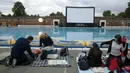 Sejumlah Penonton serius menyaksikan pemutaran film "Jaws" di pinggir kolam renang dan ada juga yang mengunakan ban karet di Brockwell Lido, London, Inggris, Kamis (17 /9/2015). (REUTERS/Luke MacGregor)