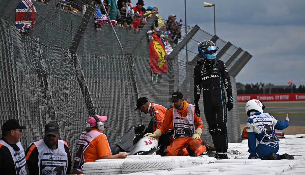 Tiba di barrier, George Russell mendapati Zhou Guanyu tengah mendapat pertolongan dari para marshall. (AFP/Ben Stansall)