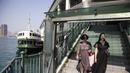 Dua wanita turun dari Star Ferry di Hong Kong (1/3/2023). Hong Kong menjadi salah satu tempat terakhir di dunia yang masih menerapkan aturan masker. (AFP/Isaac Lawrence)