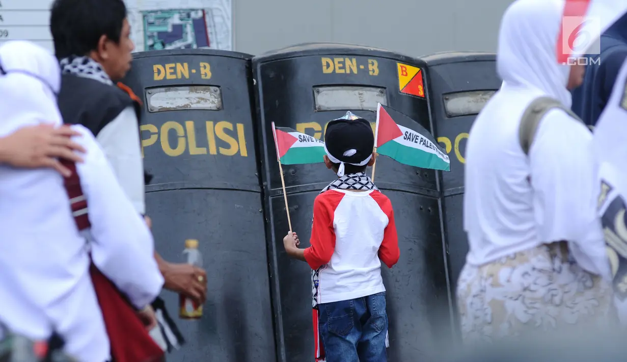 <p>Seorang anak melihat tameng polisi saat mengikuti aksi dukungan bagi negara Palestina di depan Kedubes AS, Jakarta, Minggu (10/12). Mereka memprotes keputusan Presiden Trump yang mengakui Yerusalem jadi Ibu Kota Israel. (Liputan6.com/Helmi Fithriansyah)</p>