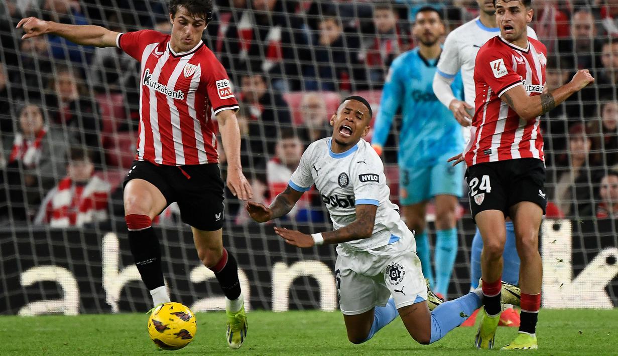 Ekspresi kesakitan pemain Girona, Savio Moreira saat berusaha melewati pemain Athletic Bilbao pada laga lanjutan Liga Spanyol 2023/2024 di San Mames Stadium, Bilbao, Spanyol, Selasa (20/02/2024) dini hari WIB. (AFP/Ander Gillenea)