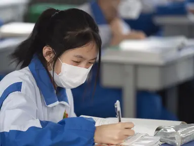 Seorang siswa yang mengenakan masker belajar di sebuah kelas sekolah menengah pertama di Yinchuan, Daerah Otonom Etnis Hui Ningxia, China barat laut, Rabu (25/3/2020). Para siswa tahun terakhir sekolah menengah pertama dan sekolah menengah atas di Yinchuan kembali masuk sekolah. (Xinhua/Yang Zhisen)