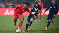 Pemain naturalisasi baru Vietnam, Nguyen Xuan Son (kiri) menggiring bola melewati pemain Thailand, Nicholas Mickelson dalam laga leg pertama final Piala AFF 2024 yang berlangsung di Viet Tri Stadium, Vietnam, Selasa (02/01/2025) waktu setempat. (AFP/Nhac Nguyen)