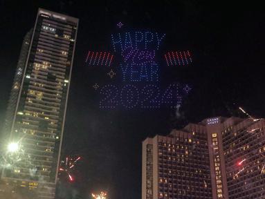 Atraksi formasi drone dan video mapping mewarnai malam pergantian tahun di kawasan Bundaran Hotel indonesia (HI), Jakarta, Senin (1/1/2024). Selain atraksi formasi drone, perayaan Tahun Baru 2024 yang dihadiri ribuan warga di lokasi tersebut juga diwarnai atraksi water mist, video mapping, serta kembang api. (Liputan6.com/Angga Yuniar)