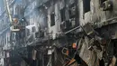 Sementara, puluhan orang lainnya masih dikabarkan hilang. Tampak dalam foto, petugas pemadam kebakaran melakukan operasi pendinginan pada bangunan yang terbakar setelah kebakaran besar di sebuah pusat perbelanjaan di Karachi pada Senin 19 Januari 2026. (Asif HASSAN/AFP)