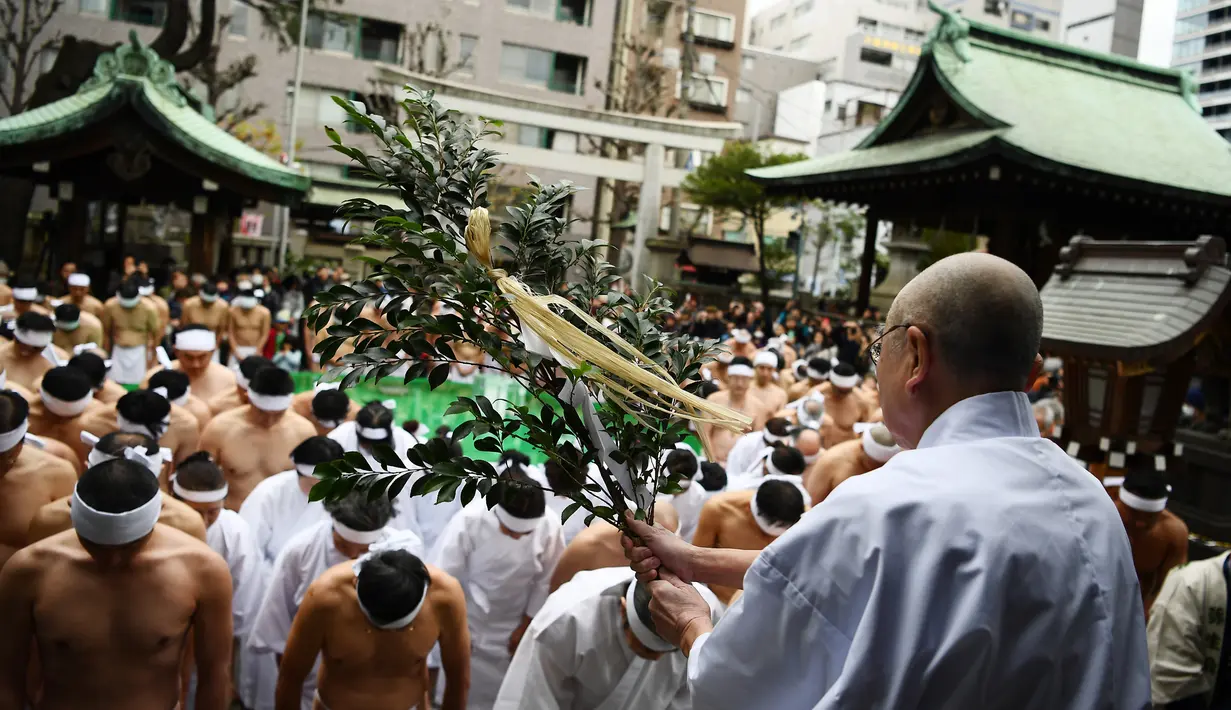 Seorang imam memberkati Shinto yang beriman dari Kuil Teppozu Inari sebelum mandi dengan air dingin untuk memurnikan jiwa dan tubuh mereka selama ritual Tahun Baru di Tokyo (12/1/2020). Sekitar 100 orang percaya Shinto ambil bagian dalam ritual tahunan tersebut. (AFP/Charly Triballeau)