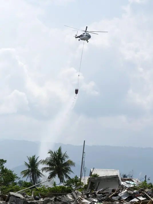 Helikopter BNPB menyemprotkan cairan disinfektan ke kawasan terdampak likuifaksi di Perumnas Petobo dan Balaroa, Palu, Sulawesi Tengah, Kamis (18/10). Penyemprotan dilakukan dengan metode water spraying. (Yusuf Wahil/AFP)