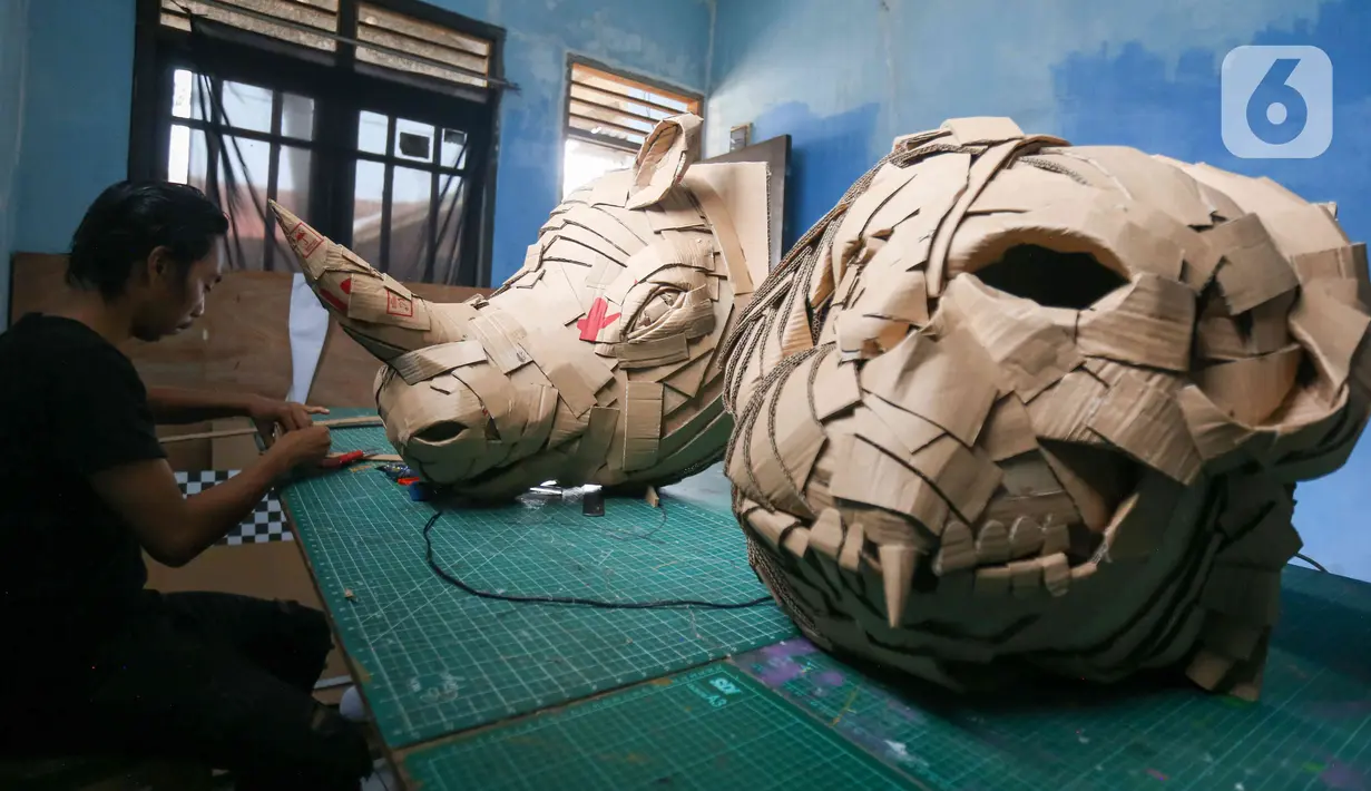 Perajin menyelesaikan pembuatan pajangan kepala badak dari kardus di Workshop Bumi Kardus, Depok, Jawa Barat, Jumat (15/7/2022). Kerajinan berbahan baku kardus tersebut dijual dengan harga Rp 400 ribu hingga Rp 60 juta tergantung tingkat kesulitan dan ukuran. (Liputan6.com/Herman Zakharia)