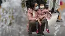 Seorang wanita dan seorang anak mengenakan masker untuk mengekang penyebaran COVID-19 di Beijing, China, Minggu (11/10/2020). Meski penyebaran COVID-19 hampir diberantas di China, pandemi masih melonjak di seluruh dunia dengan jumlah kematian yang terus meningkat. (AP Photo/Andy Wong)