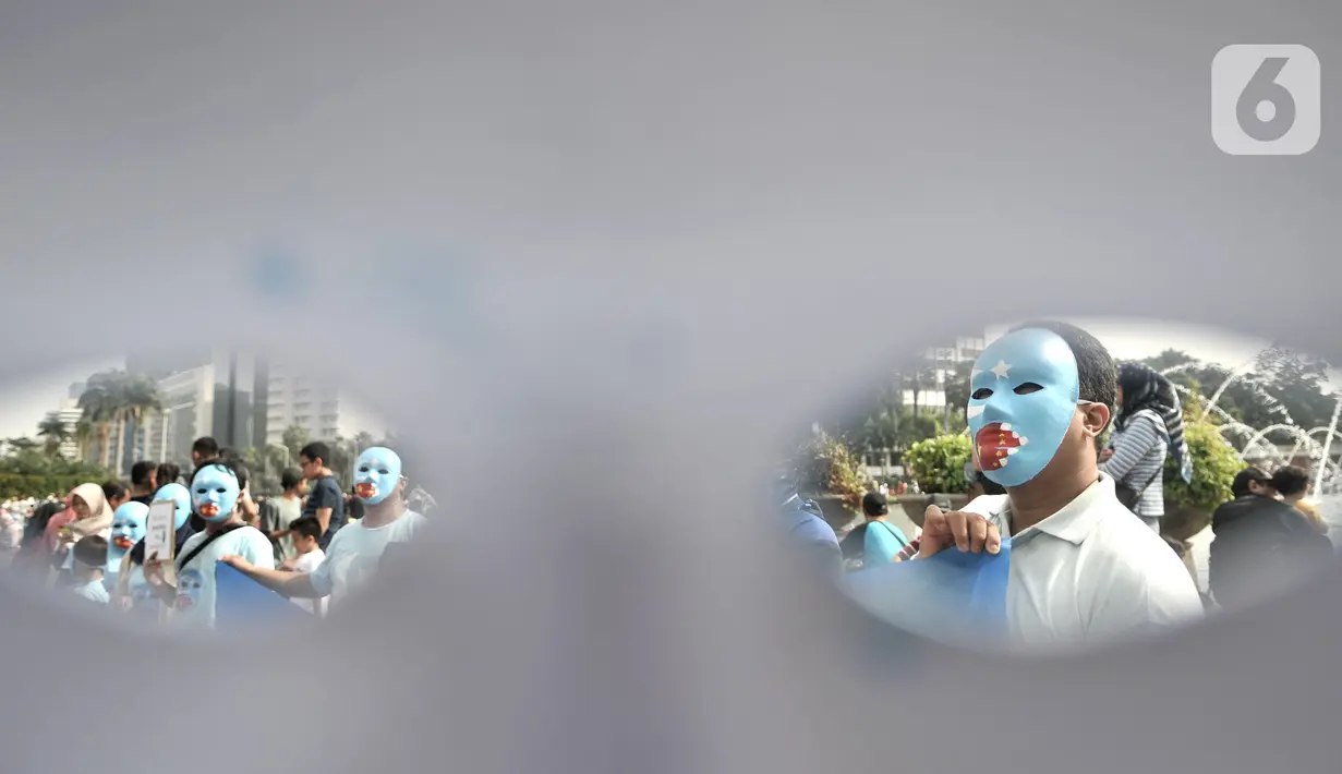 Warga mengenakan topeng bendera Turkestan Timur saat menggelar Aksi Save Uighur selama CFD, Jakarta, Minggu (22/12/2019). Aksi digelar sebagai bentuk peduli terhadap muslim Uighur di Xinjiang yang diduga terus mengalami tindakan kekerasan oleh pemerintah China. (merdeka.com/Iqbal S. Nugroho)