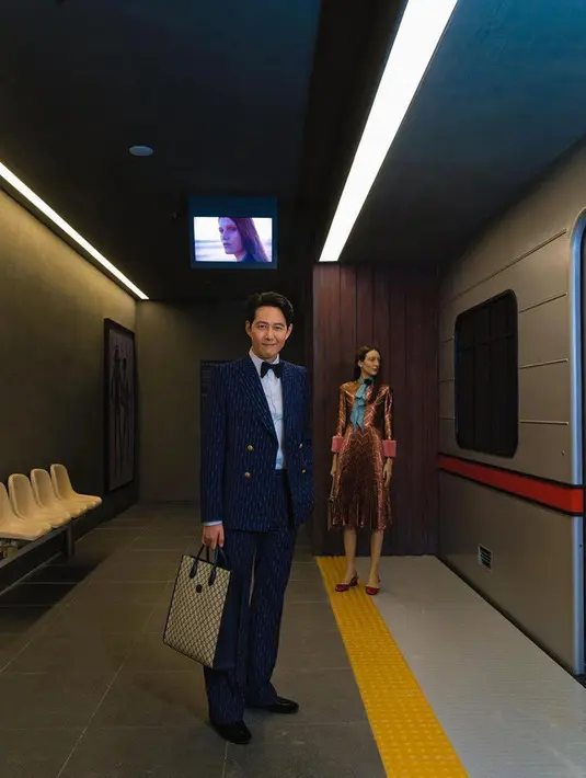 Lee Jung Jae memadukan penampilannya dengan kemeja bernuansa baby blue, dasi kupu-kupu beludru hitam, sepatu Horsebot beludru hitam, tote bag GG Supreme kanvas medium berwarna krem dan biru. Foto: Document/Gucci.