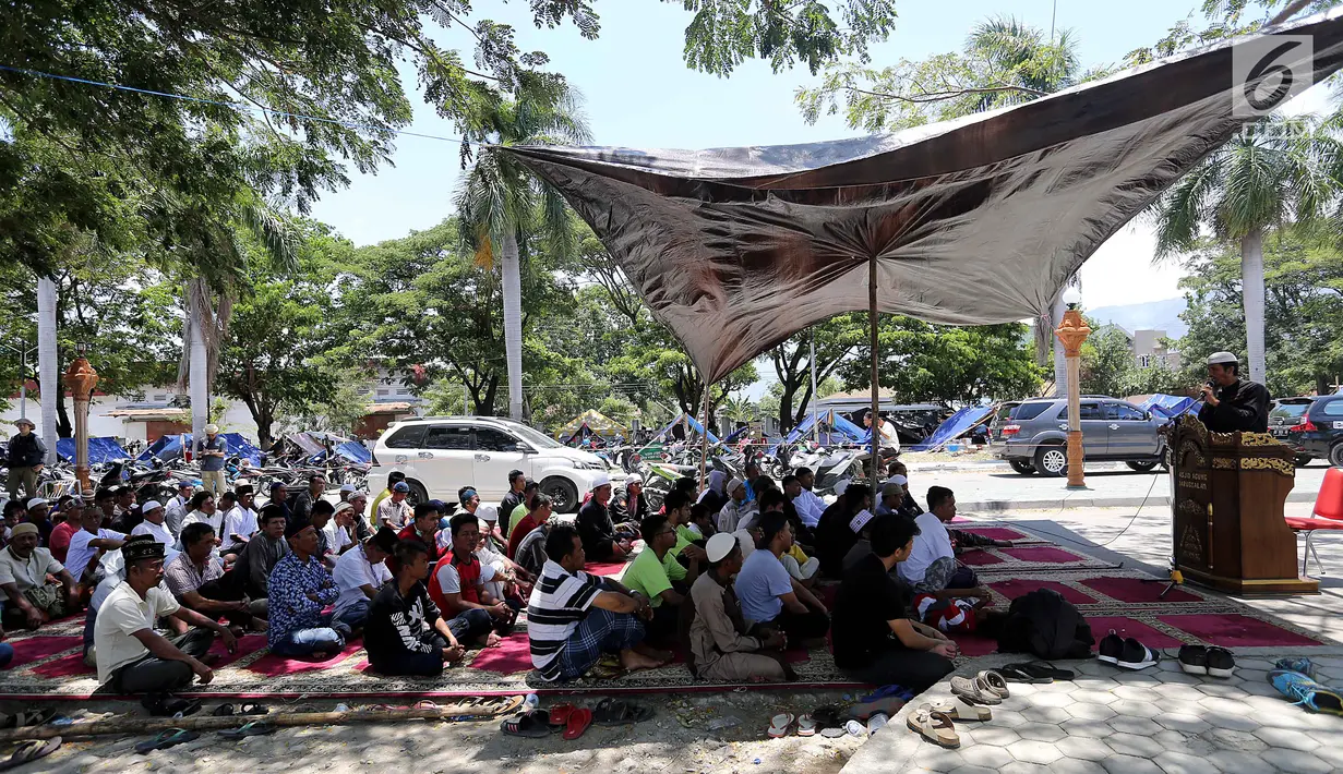 Ratusan pengungsi mendengarkan khotbah salat Jumat pascagempa dan tsunami di Lapangan Masjid Agung Daru Salam, Palu, Jumat (5/10). Sebuah terpal cokelat dan karpet merah digelar di belakang masjid. (Liputan6.com/Fery Pradolo)