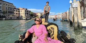 Seperti saat naik gondola ini, ia tampil fresh dengan dress pink, dipadu dengan mini bag, dan bando.