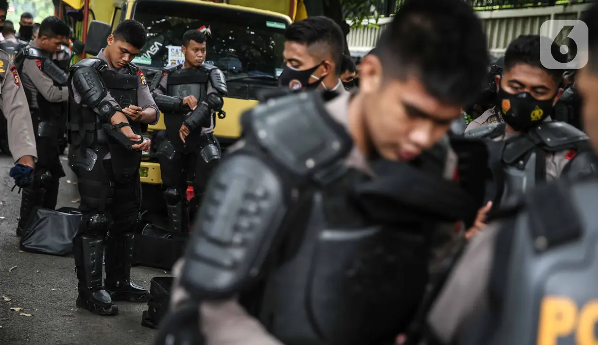 Personel Brimob bersiap mengenakan perlengkapan pelindung diri di Kawasan Bundaran HI, Jakarta, Selasa (13/10/2020). Sebanyak kurang lebih 12 ribu personel gabungan TNI, Polri dan Pemprov DKI Jakarta diterjunkan mengawal aksi tolak Undang-Undang Cipta Kerja Omnibus Law. (Liputan6.com/Faizal Fanani)