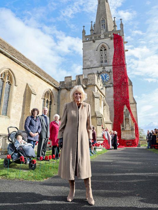 Ratu Inggris, Camilla, bereaksi setelah memasang bunga poppy terakhir untuk melengkapi rangkaian 10.000 bunga poppy yang menghiasi menara gereja di Gereja St. Bartholomew di Corsham, Inggris pada Selasa 28 Oktober 2025. Ratu Camilla menyempatkan berfoto berlatar belakang Gereja St. Bartholomew di Corsham, Inggris yang dikelilingi ribuan bunga poppy. (Chris Jackson/POOL/AFP)