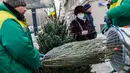 Seorang pria membantu mengemas pohon untuk perayaan Tahun Baru di sebuah pasar di pusat kota Moskow, Rusia (27/12/2020). (Xinhua/Maxim Chernavsky)