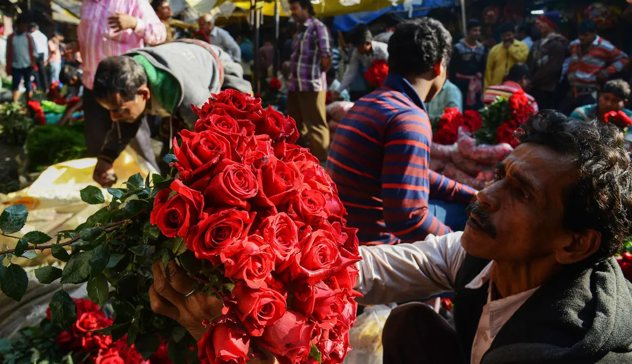 Pedagang merapihkan bunga mawar saat mereka menunggu pelanggan di pasar bunga grosir di Kolkata, India (7/2). Jelang perayaan hari Valentine, bunga mawar banyak diburu dari tanggal 7 Februari dengan ditandai dengan Rose Day. (AFP Photo/Dibyangshu Sarkar)