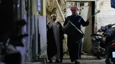 Wissam Ali (kanan), seorang "mesaharati" atau penyeru subuh berusia 22 tahun, saat membangunkan orang-orang untuk makan sebelum matahari terbit, selama bulan suci Ramadan, di lingkungan miskin distrik Fadhil di Baghdad, Irak, Senin 23 Februari 2026. Mesaharati (juga dikenal sebagai Al-Mesaharati) merupakan sebutan bagi seseorang yang bertugas membangunkan umat Muslim untuk makan sahur sebelum waktu Subuh tiba selama bulan Ramadan. (AP Photo/Hadi Mizban)