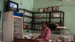Penjaga menonton televisi sebuah konferensi pers dari Pejabat Uni Afrika di sebuah restoran sambil menunggu hasil resmi pemilihan umum Kenya di Kisumu (10/8). Berdasar laporan, Uhuru Kenyatta masih unggul dari Raila Odinga. (AFP Photo/Jennifer Huxta)